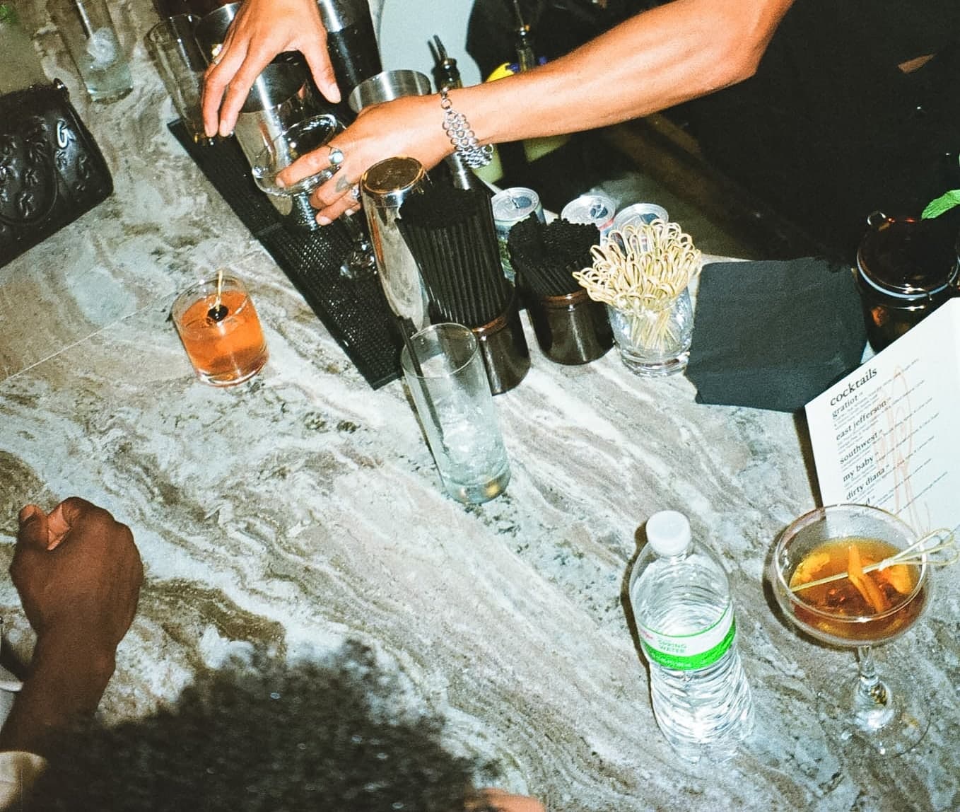 Hands, cocktails and a menu card on the marble bar