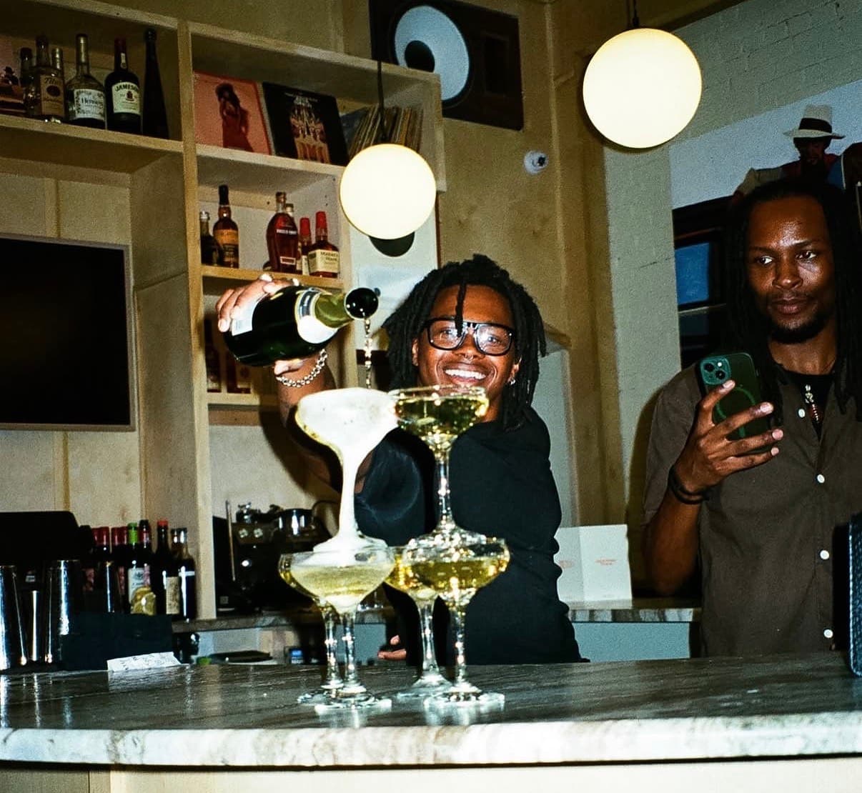 A bartender pouring champagne into a tower of coupes